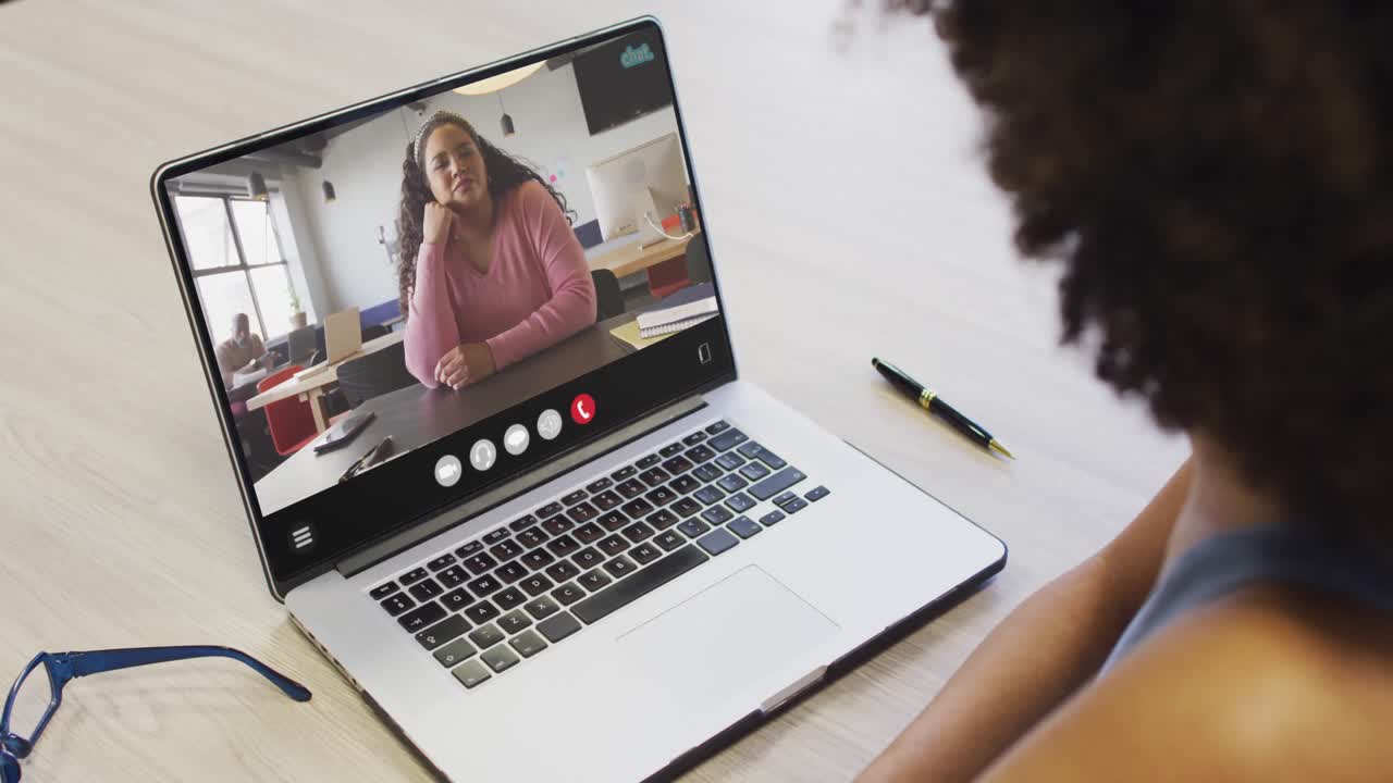 African american woman using laptop for video call, with business colleague on screen