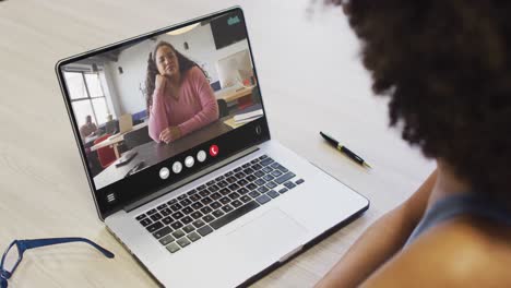 african american woman using laptop for video call, with business colleague on screen