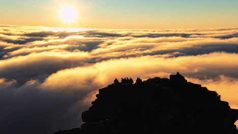 aerial, drone view orbiting around hikers, on the summit of the on mount hassell mountain, above clouds, during sundown, in west australia