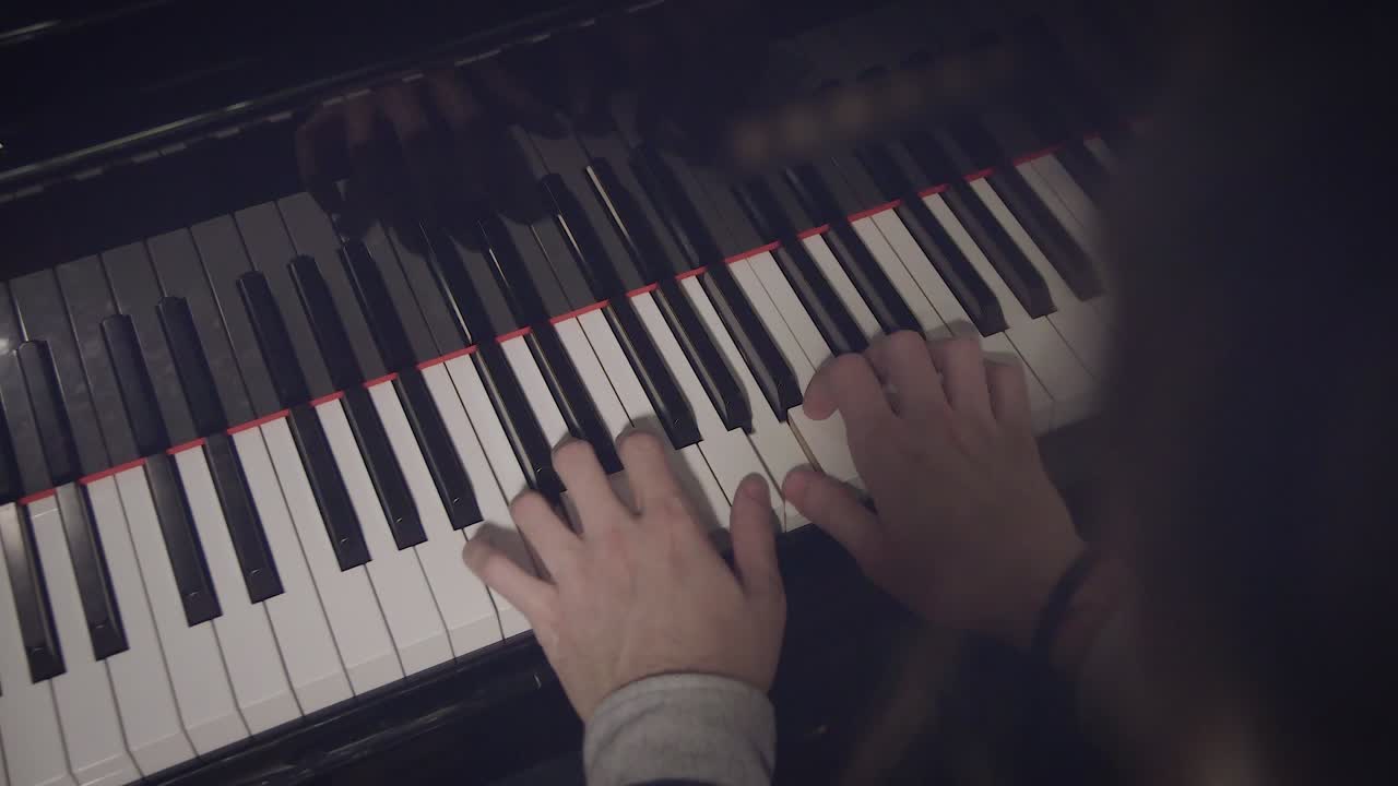 Male pianist performing a song on piano with low light and top view.