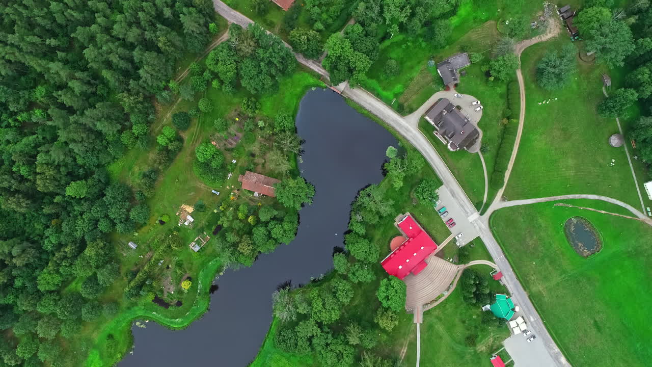 дронный вид наклоняется вниз на сельское сообщество, окруженное деревьями с небольшим озером в центре