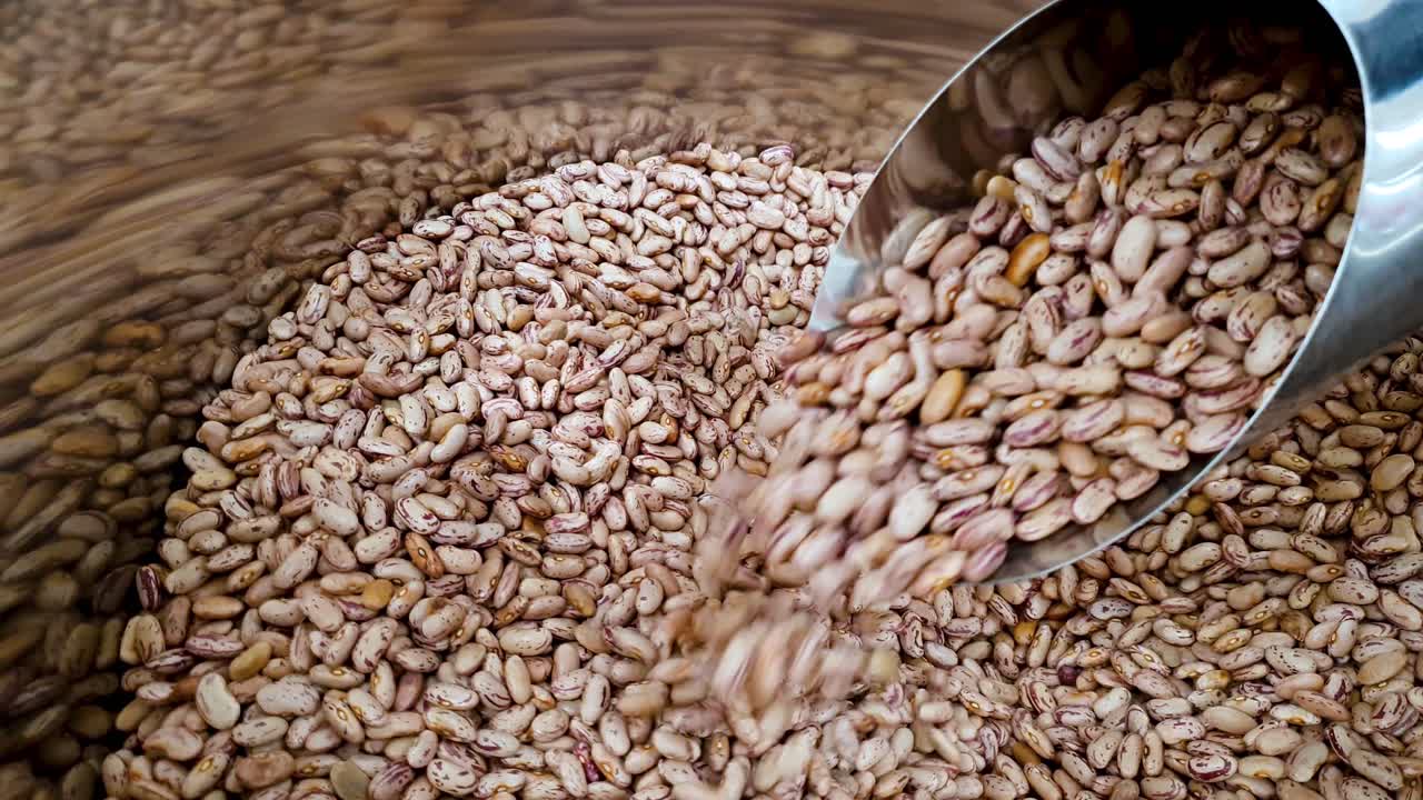 primer plano de frijoles rojos crudos que caen de una taza en un contenedor en el supermercado