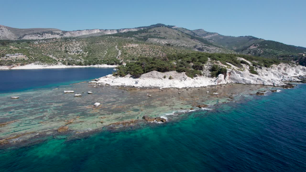 vista aérea giratoria de una enorme pared de mármol en aliki antigua cantera de mármol con altos picos de montaña en el fondo y el mar mediterráneo en primer plano, colores vivos, thassos, grecia