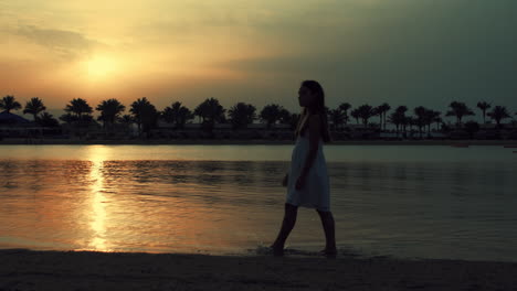 young woman walking at beach. barefoot girl spending sunrise time at seaside.