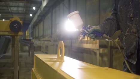 industrial worker spray painting metal beam