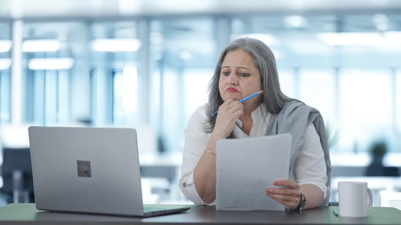 confundida directora india senior leyendo informes de negocios