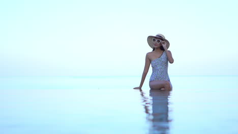 una hermosa joven sentada en el borde invisible de una piscina infinita da la apariencia de flotar en el aire