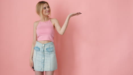 young woman in pink top and light blue skirt presenting product