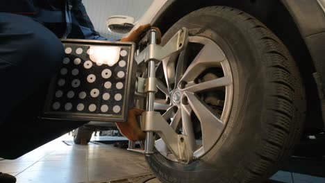 auto mechanic installing sensor during suspension adjustment and automobile wheel alignment work at repair service station. close up