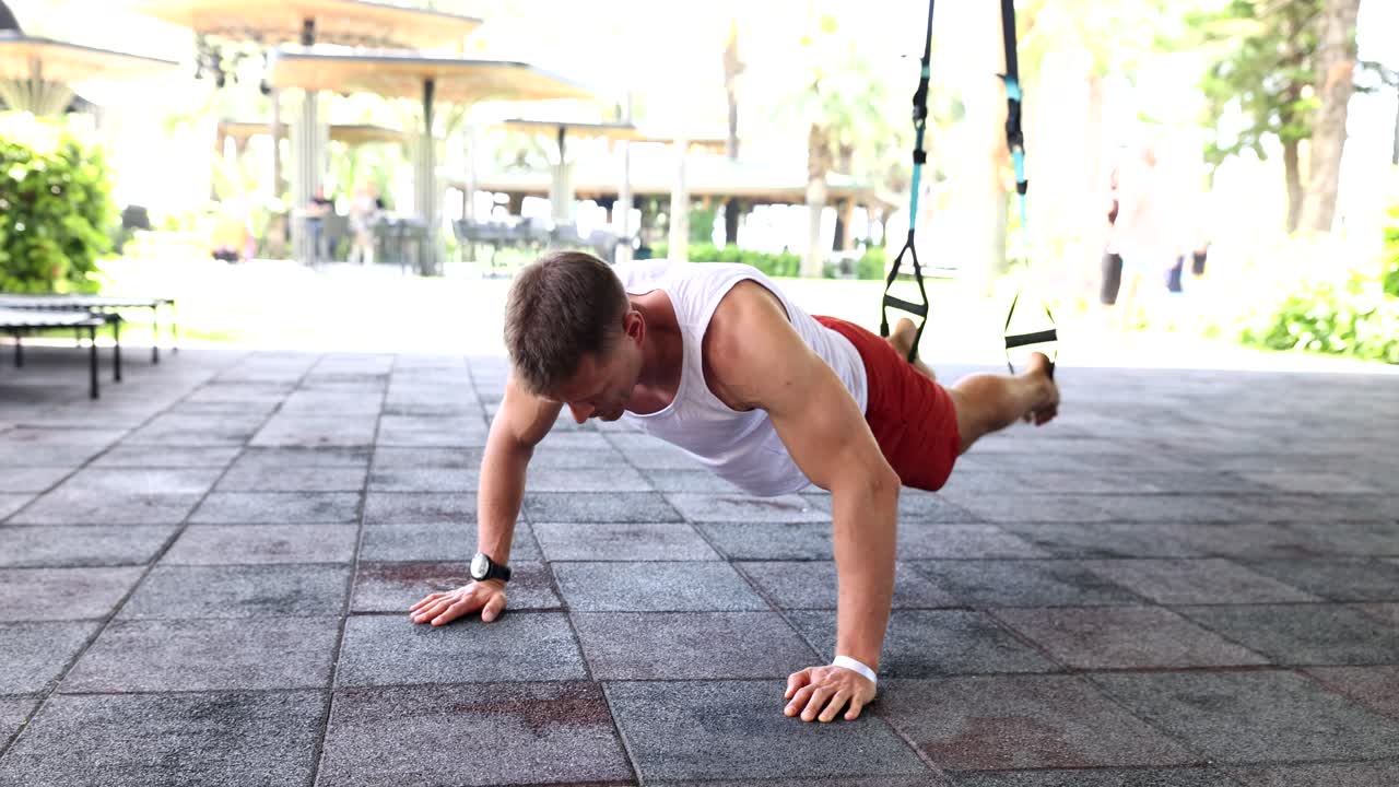 Atleta che esegue esercizi per gli addominali a terra con le TRX in un campo sportivo