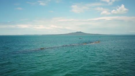 view of rangitoto island from the sea with a distant boat