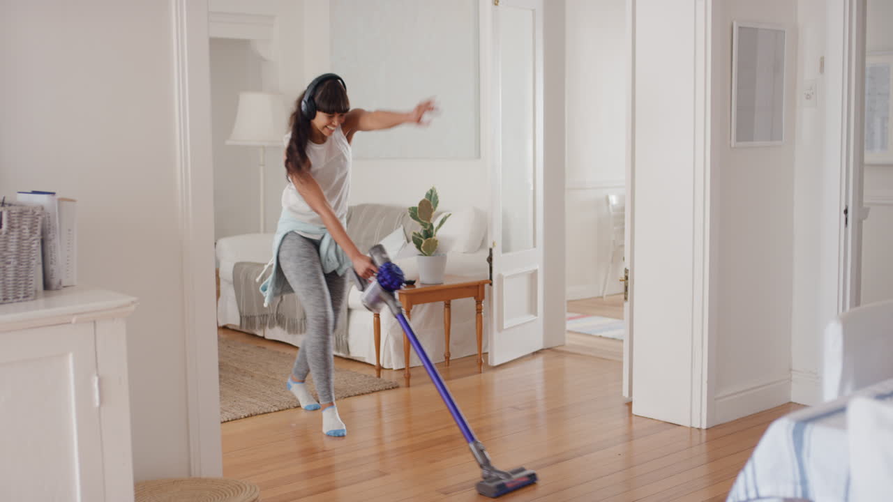adolescente feliz bailando con la aspiradora haciendo tareas limpiando la casa divirtiéndose baile tonto escuchando música usando auriculares disfrutando de una mañana de fin de semana despreocupada en casa 4k