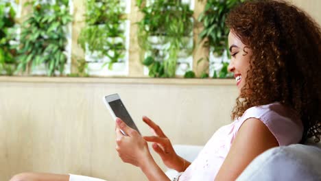 Female-executive-sitting-on-sofa-and-using-digital-tablet