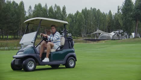 two men riding in a golf cart on a golf course