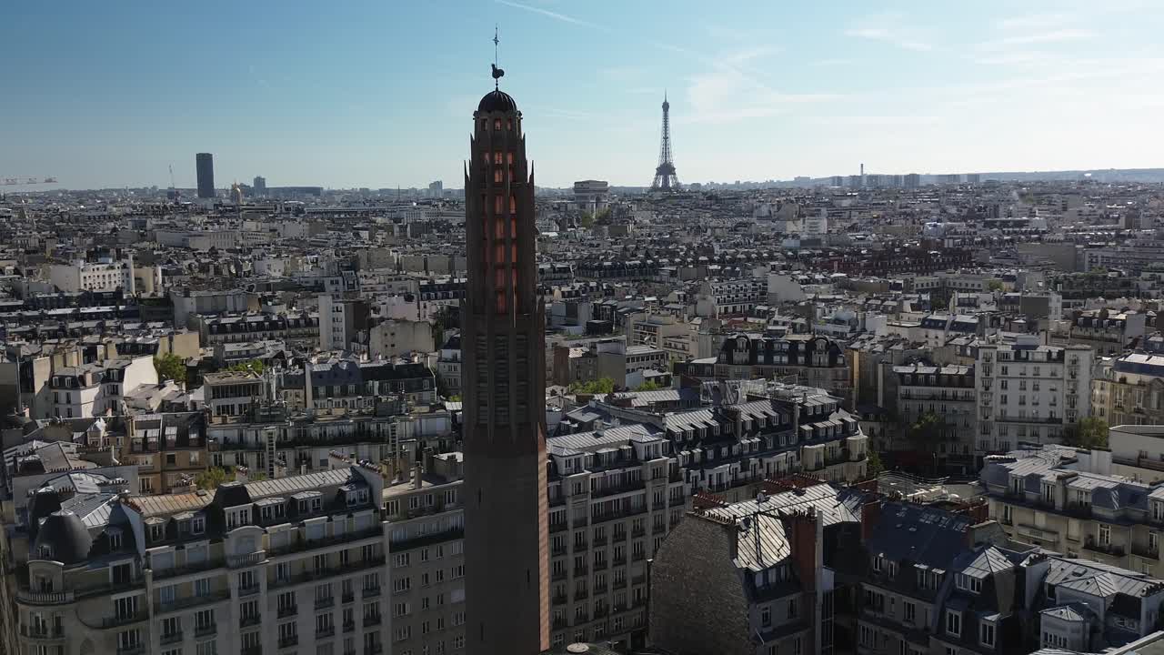 Drone flying near bell tower of Sainte-Odile church with Tour Eiffel and Montparnasse in background, Paris in France