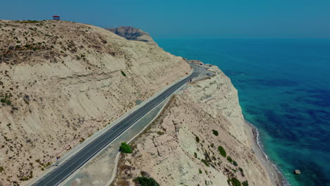 Experimente-El-Cautivador-Encanto-Del-Mediterráneo-Desde-El-Punto-De-Vista-De-La-Roca-Afrodita,-Un-Vuelo-De-Drones-Sobre-Su-Pintoresca-Carretera,-Mostrando-El-Magnífico-Mar-De-Chipre