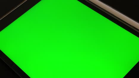 hombre mirando una tableta de pantalla verde en casa