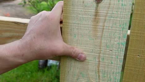 man using pneumatic nail gun on wooden fence, close up view