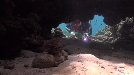 scuba diver placing gopro camera inside underwater cave