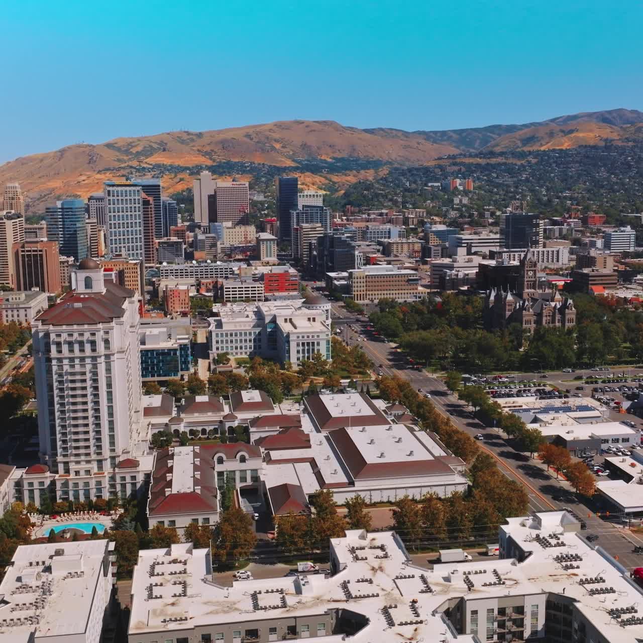 Rising over the beautiful contemporary buildings of Salt Lake City, Utah, USA. Lively traffic along the city from aerial view. Mountains at backdrop