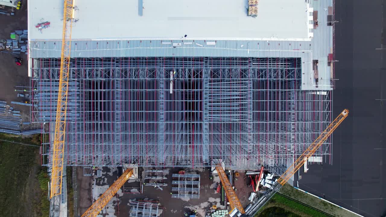 Descending Drone Shot of Large Steel Building Roof Being Built at Construction Site, Aerial View