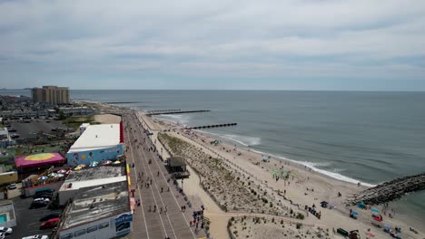 Toma-Aérea-Sobre-Un-Paseo-Marítimo-De-Jersey-Shore-Con-Olas-Rompiendo-En-La-Playa