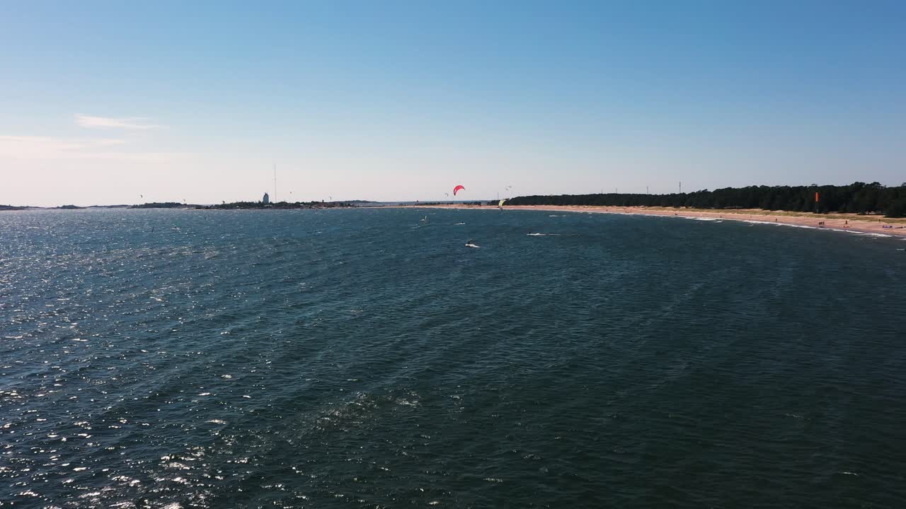Aerial view of people Kite sailing, at a beach, warm, windy, summer day, in Scandinavia - dolly, drone shot
