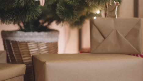 close up view of a person placing presents under christmas tree decorated with elements and christmas lights