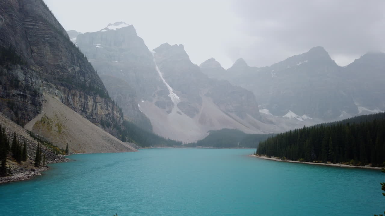 agua azul turquesa surrealista del lago moraine en un día nublado en alberta, canadá - toma panorámica lenta
