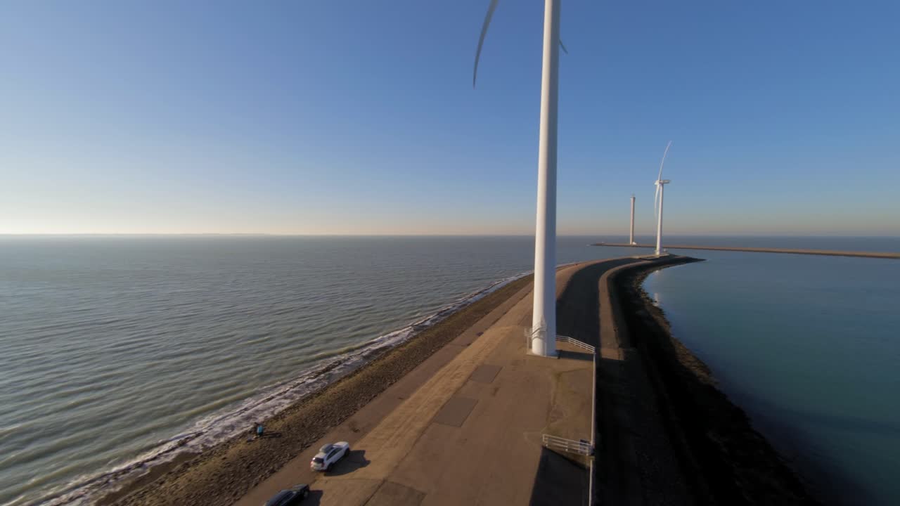 Close-up of a large windturbine on a dyke in the middle of the sea during sunset