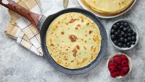 Delicious-pancakes-on-stone-frying-pan--Placed-on-table-with-various-ingredients