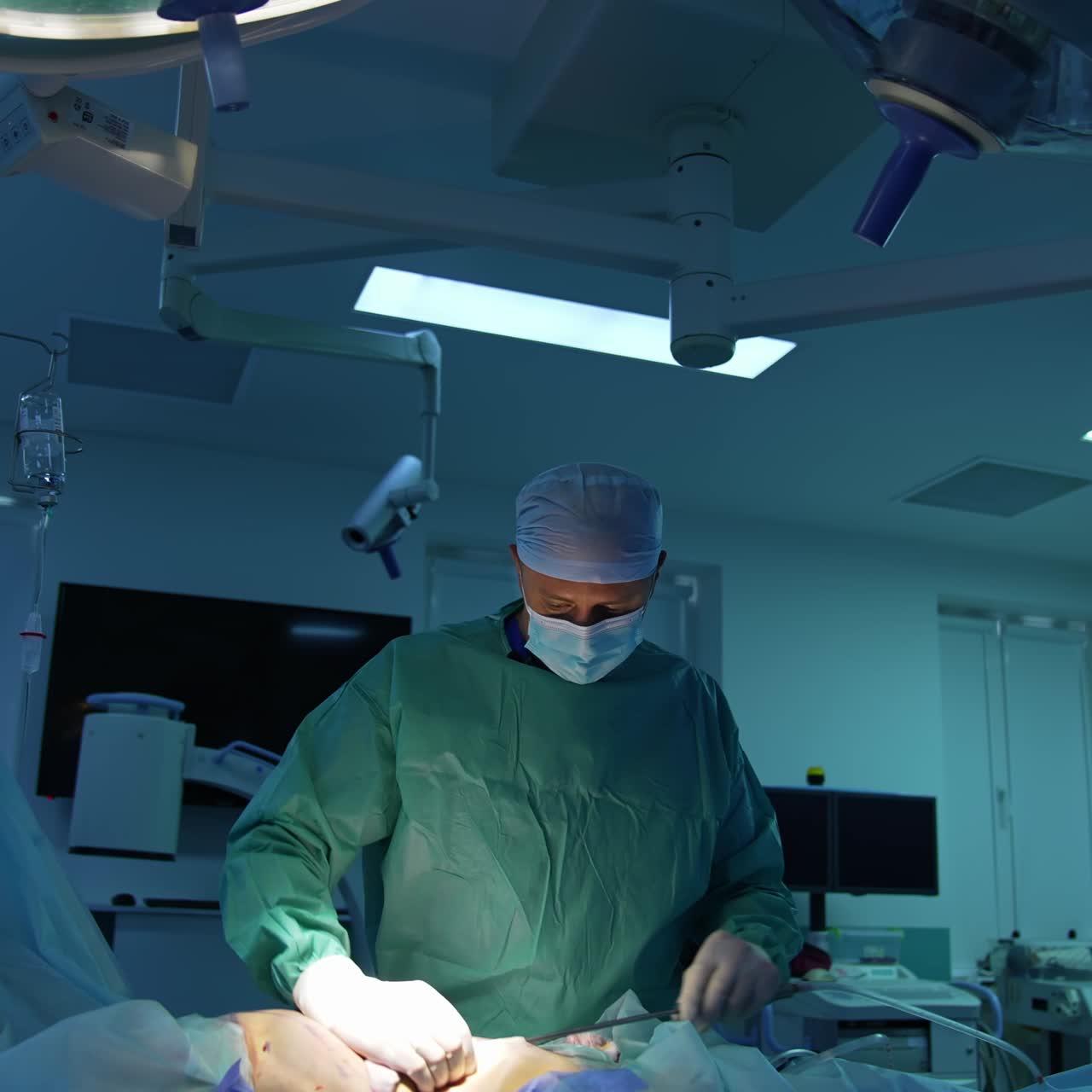 Doctor performs surgical procedure in operating room. Professional surgeon doing abdominal liposuction to a patient under medical lamps