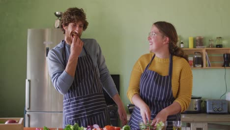 happy caucasian couple cooking together in kitchen