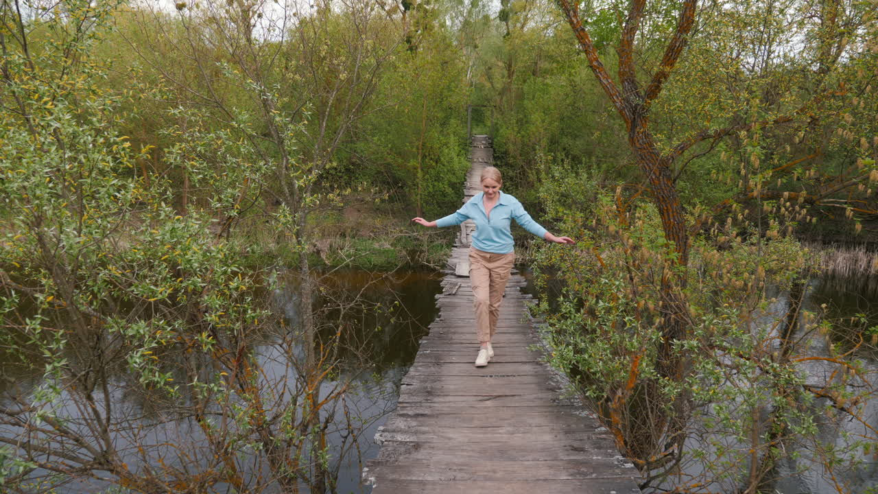 강 의 숲 속 의 나무 다리 를 가로질러 고 있는 여자