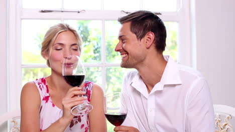 una pareja feliz bebiendo vino rojo juntos.