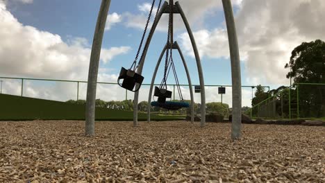 empty park swings move to and fro during the day at the kids playground