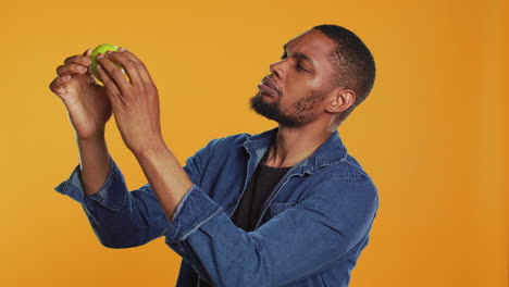 Young-man-inspecting-a-freshly-harvested-green-apple-in-studio