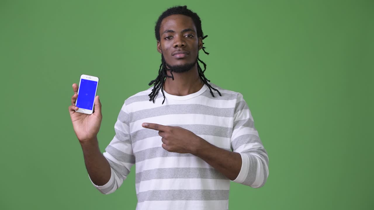 Young handsome African man with dreadlocks against green background