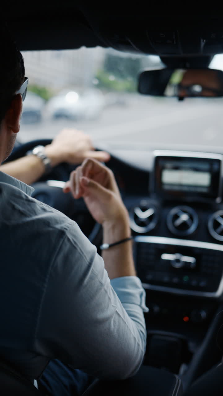 Man wearing sunglasses talking and gesticulating white driving a car. Vertical
