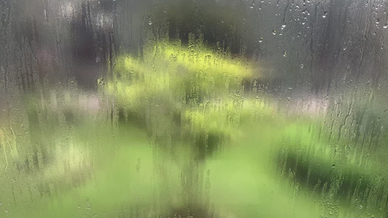 Rain drop on window over blurred nature garden background, rainy season background idea