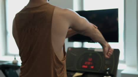 unrecognizable man walking on treadmill in health centre and warming up arms and elbow joints, stretch muscles preparing for workout - close-up slow motion