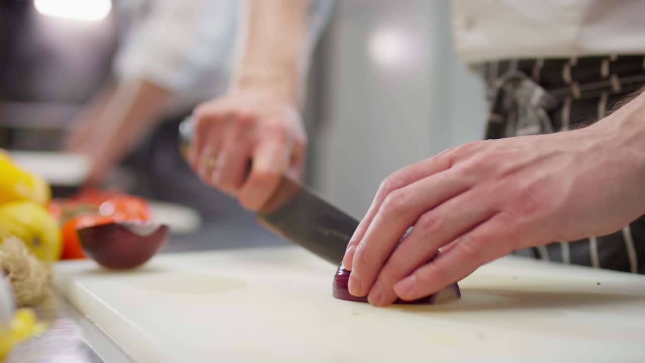 Hands of Chef Cutting Red Onion