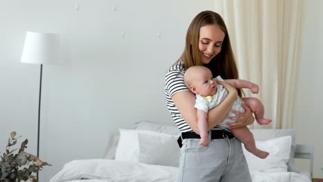 the concept of a modern young family in a white apartment. mom puts the baby to bed singing him a lullaby