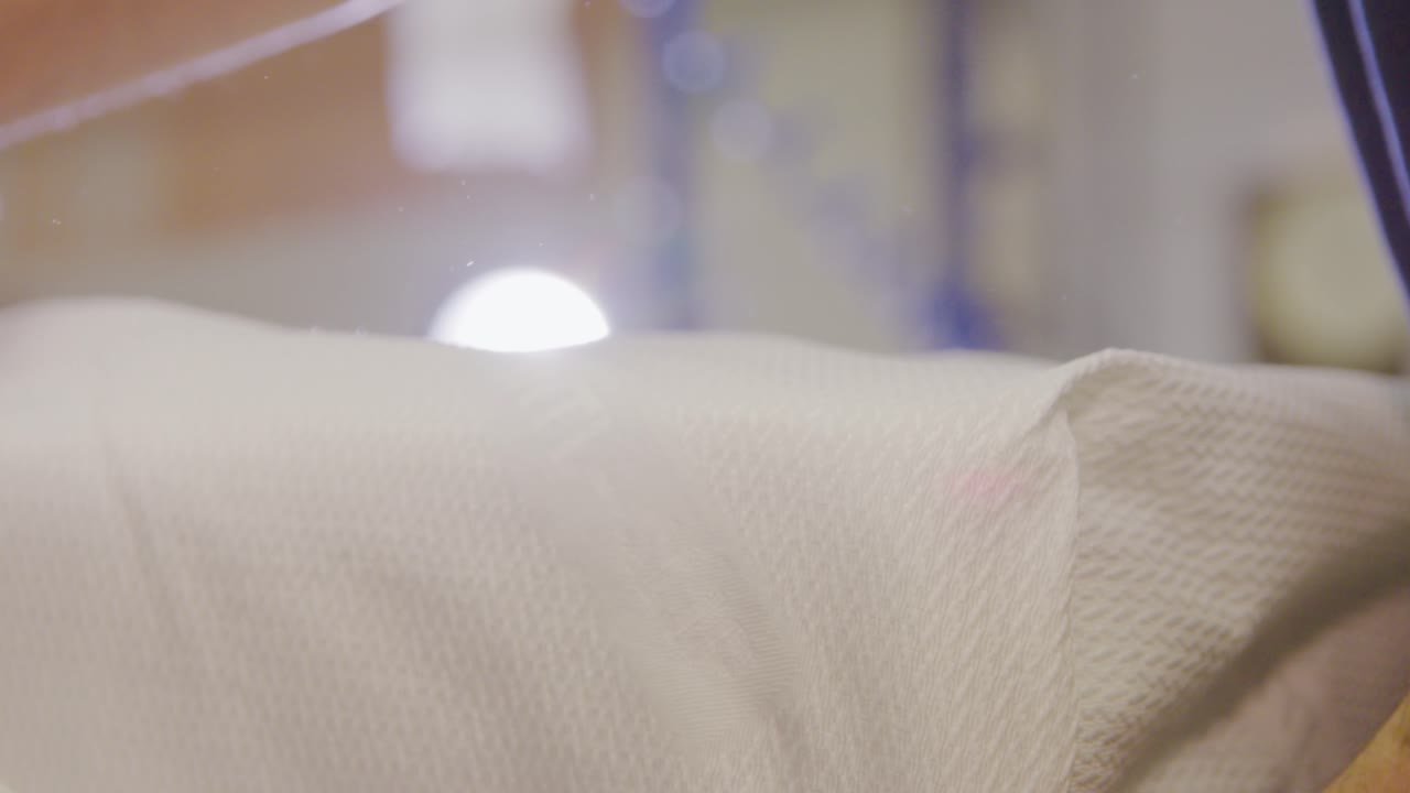 manos arreglando un colchón blanco en una fábrica de camas, fondo borroso