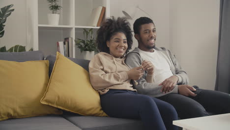 young couple having fun while watching a movie on tv