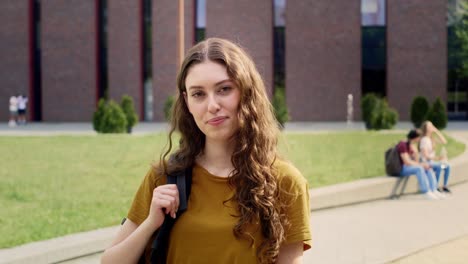 Portrait-of-female-university-student-standing-outside-the-university-campus