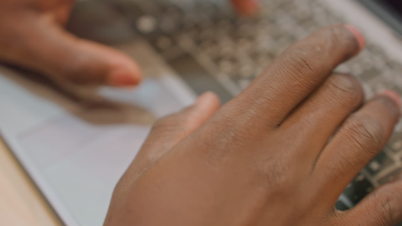 Programmer at work. Software engineer typing on laptop in dimly lit office setting. Professional developer rapidly entering code on keyboard with screen displaying blurred programming script