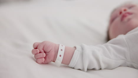 Baby,-new-born-and-hand-with-bracelet-on-bed