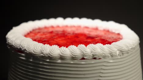 plano de detalle de cerca de las bayas de fresa pastel de jalea con crema en una mesa giratoria con fondo negro bucle delicioso dulce delicioso