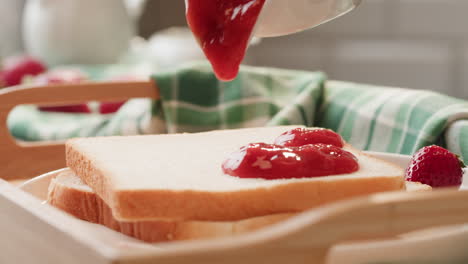 pouring strawberry jam on toast